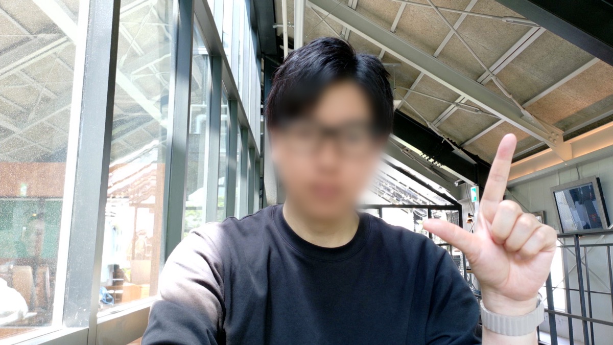 手でL字を作る人物