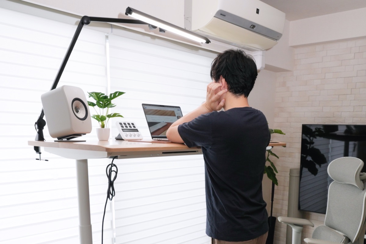 デスクにもたれかかる男性