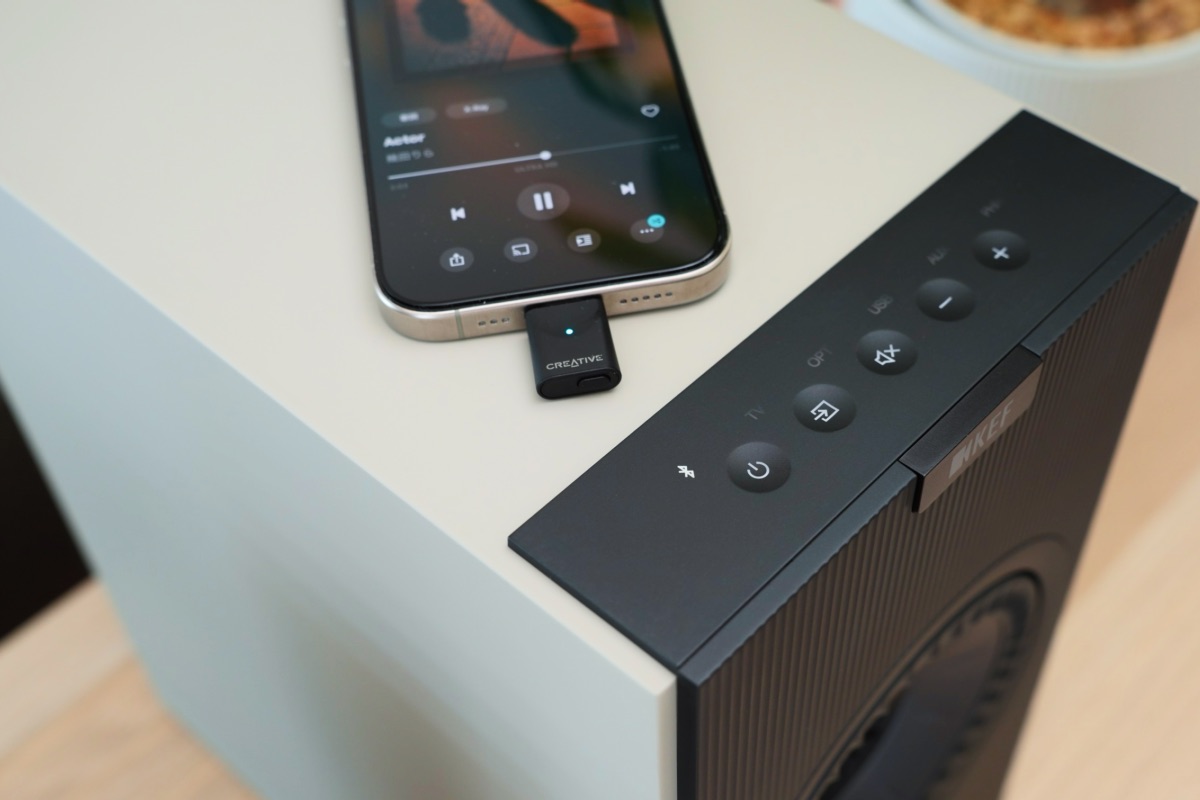 aptX対応トランスミッターを装着したiPhoneと、Bluetooth接続サインの点灯したKEF Coda W