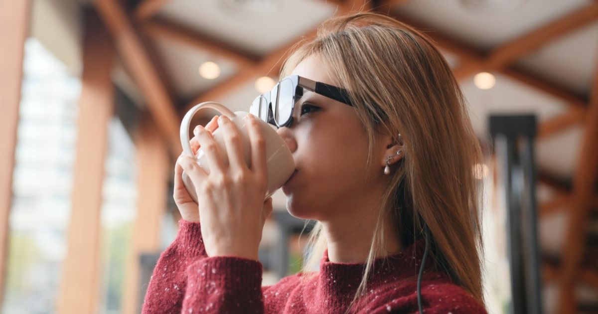 コーヒーを飲みながらXREAL 1Sを楽しむ女性