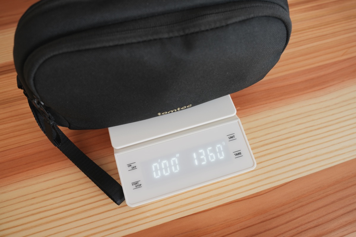 中身が入ったtomtoc ガジェットポーチ Mと136gを示す計量器